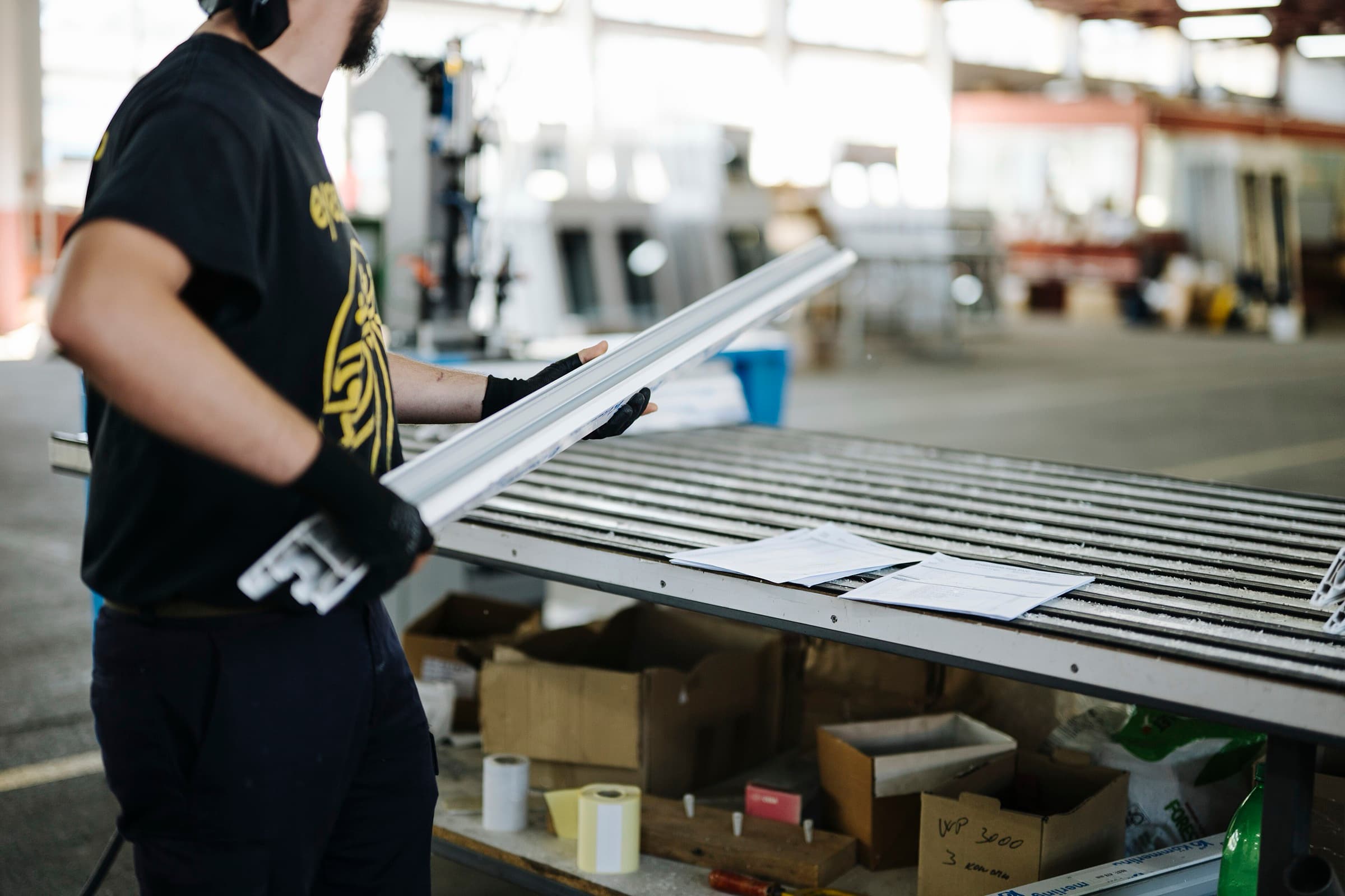 Worker handling fabricated profiles in an industrial workshop
